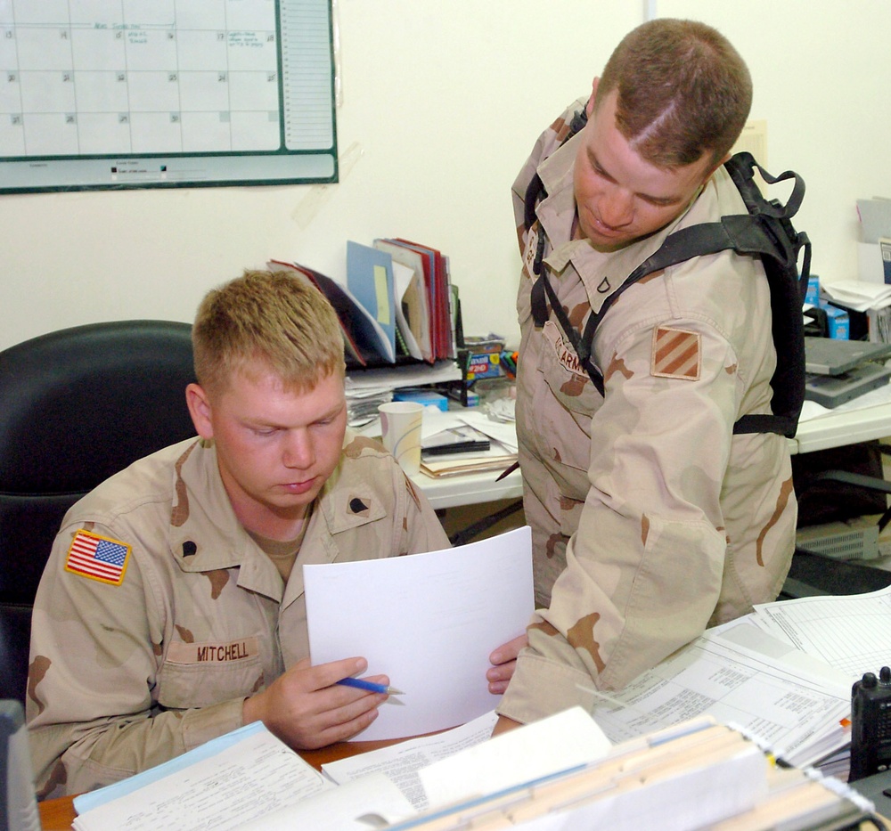 SPC Mitchell and PFC George go over supply forms in the battalion supply of