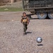 Iraqi chid chases a ball behind  a Stryker Combat Vehicle