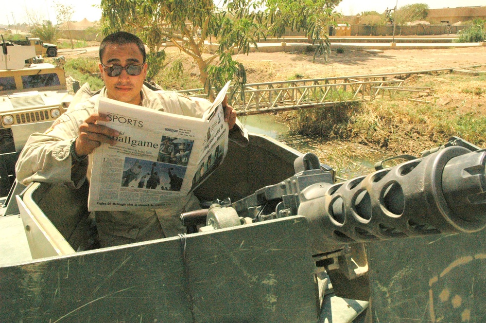 PFC Curbow reads a newspaper while he waits in the turret of his truck