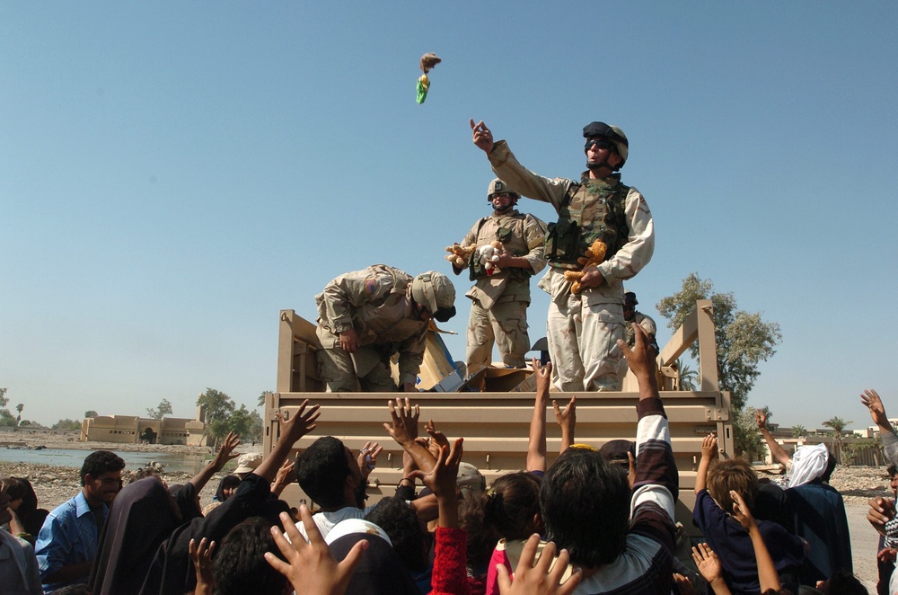 Soldiers toss stuffed animals to children