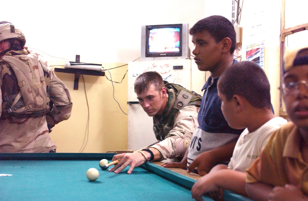 SSG Kenneth Stephens plays a game of pool with Iraqi youth