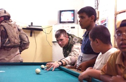 SSG Kenneth Stephens plays a game of pool with Iraqi youth