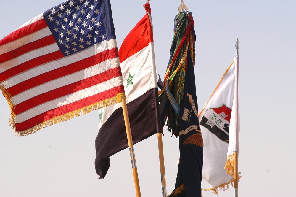 The United States Colors and the Iraqi flag fly over Forward Operating Base