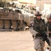 SSG Emery and PFC Little walk in front of their Stryker during a