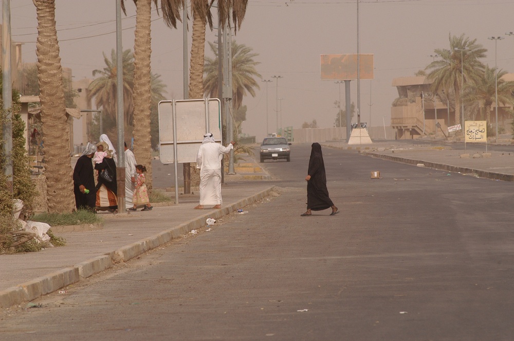 Tikrit civilians cross the street ahead of a car containing explosives desi