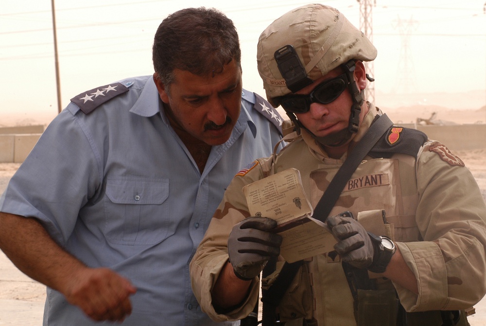 SPC Bryant uses a language guide book to communicate with a local Iraqi pol