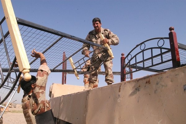 Soldiers load beds onto an Iraqi army cargo truck