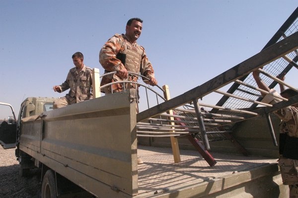 Soldiers load beds onto an Iraqi army cargo truck