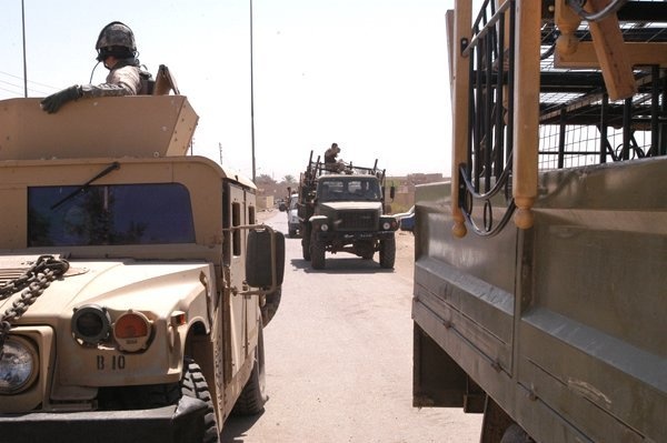 Iraqi army cargo trucks pass by a gun truck