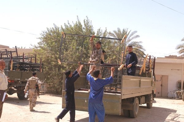 A Soldier and workers from Balad General Hospital unload beds