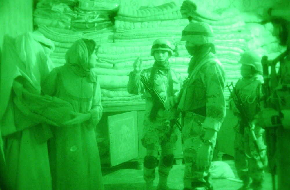 An Iraqi Soldier instructs an Iraqi woman to get keys for a locked box foun