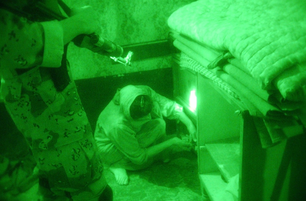 An Iraqi Soldier watches an Iraqi woman unlock a storage box