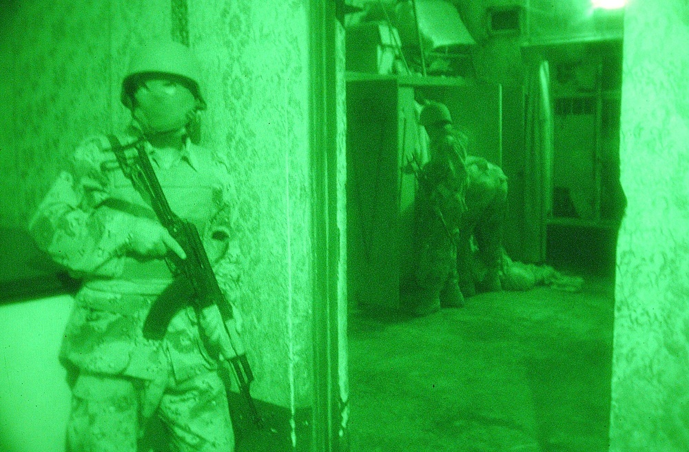 An Iraqi Soldiers atnad guard while other Soldiers search a closet
