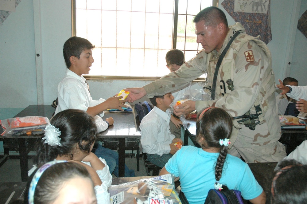 Staff Sgt. Mario Alfaro  hands out school supplies