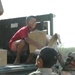 Children rush to help Soldiers unload boxes packed with school supplies