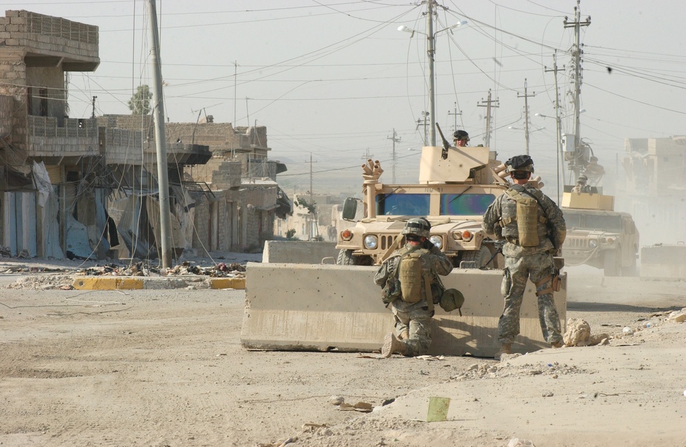 Two Paratroopers watch as two HMMWVs pass their patrol