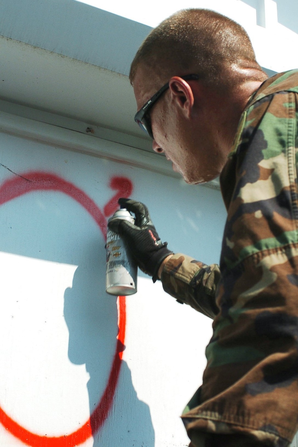 A Soldier paints a house that has been searched