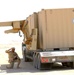 A US Soldier directs the lifting of a storage unit off a flatbed trailer