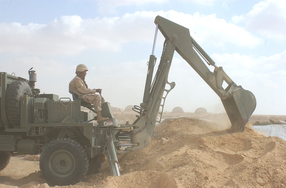 A US Soldier uses a backhoe during construction of a fueling point