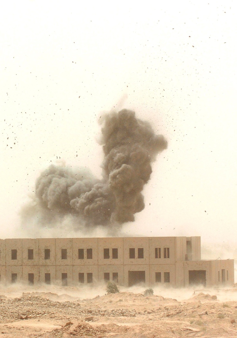 A cloud of smoke and debris rise from the impact of an MLRS rocket