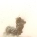 A cloud of smoke and debris rise from the impact of an MLRS rocket