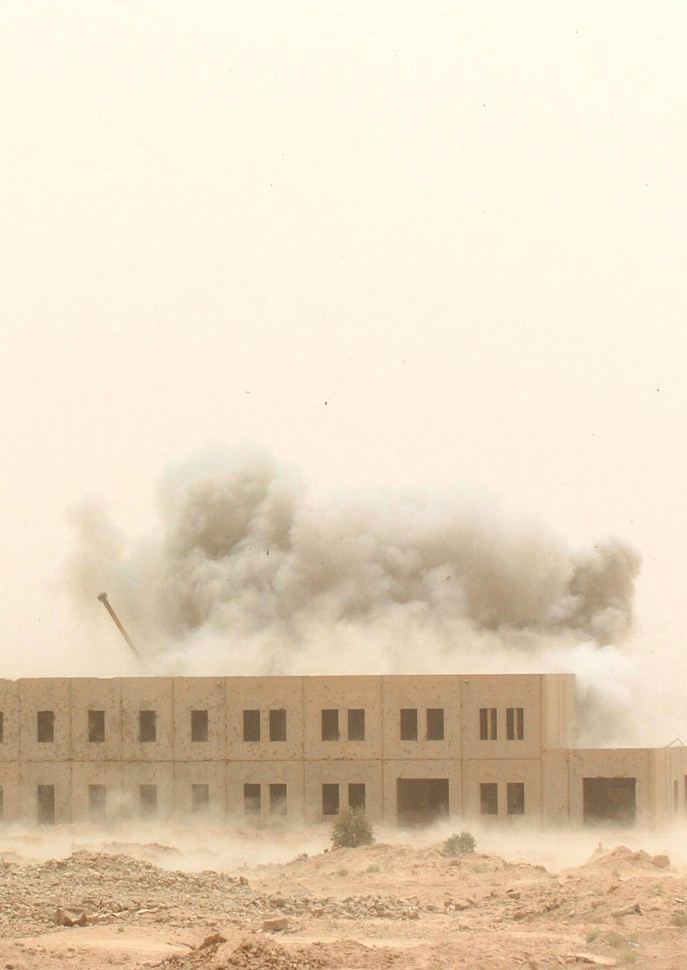 A cloud of smoke and debris rise from the impact of an MLRS rocket