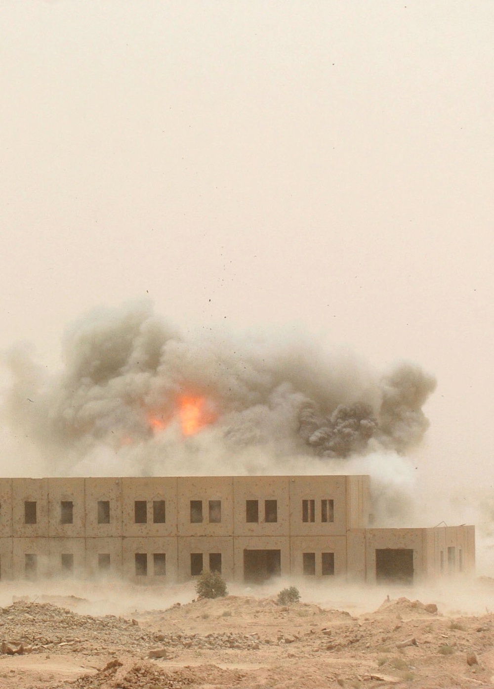 A cloud of smoke and debris rise from the impact of an MLRS rocket