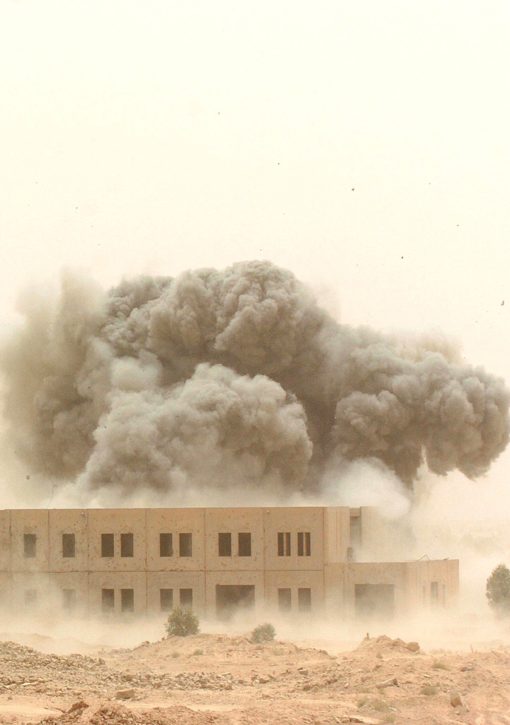 A cloud of smoke and debris rise from the impact of an MLRS rocket