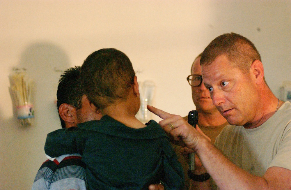 Maj. Ben E. Solomon shows a small boy that he wants to examine his eyes