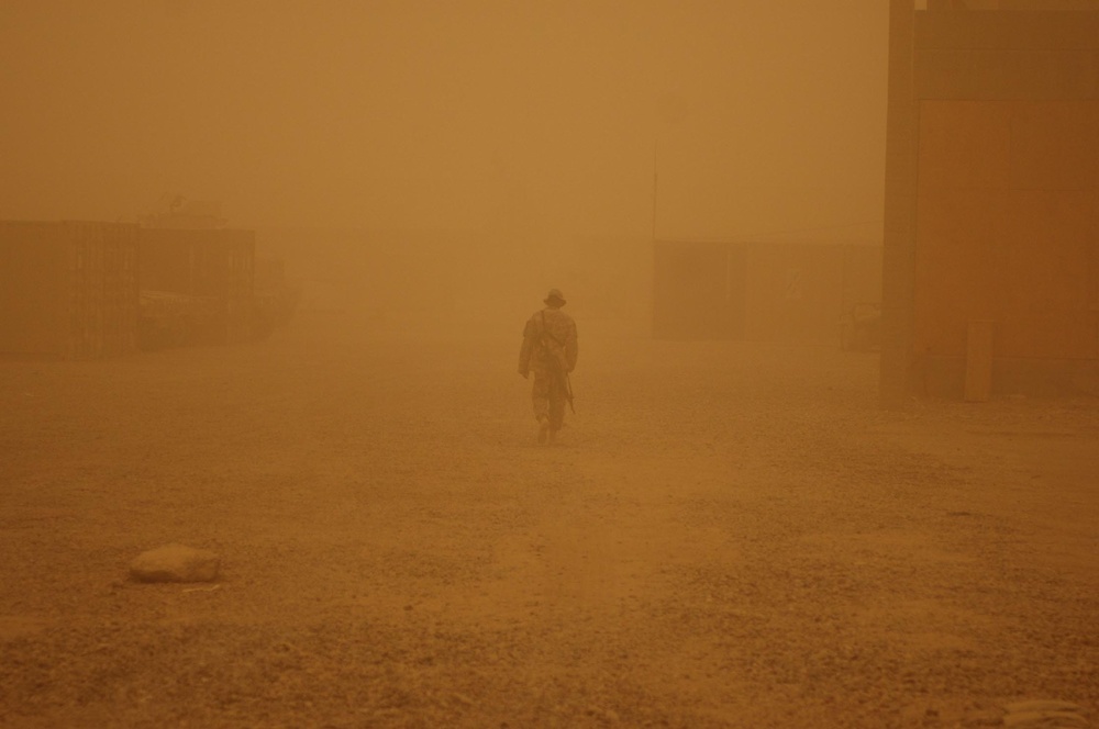 A lone Soldier walks through a fog of sand