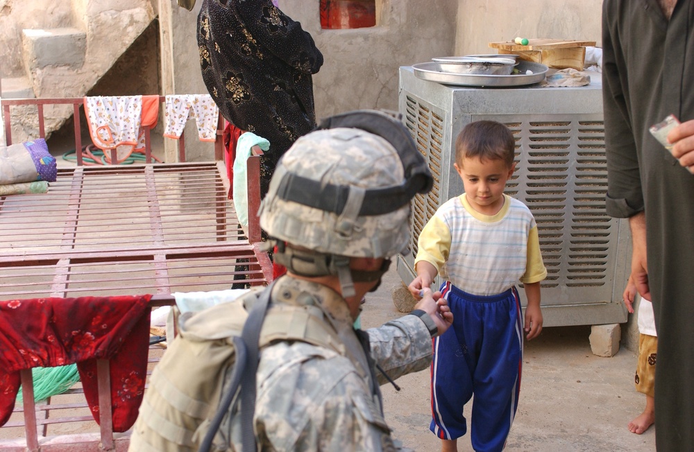 Sgt. Tyson R. Rolland gives a piece of candy to a young boy