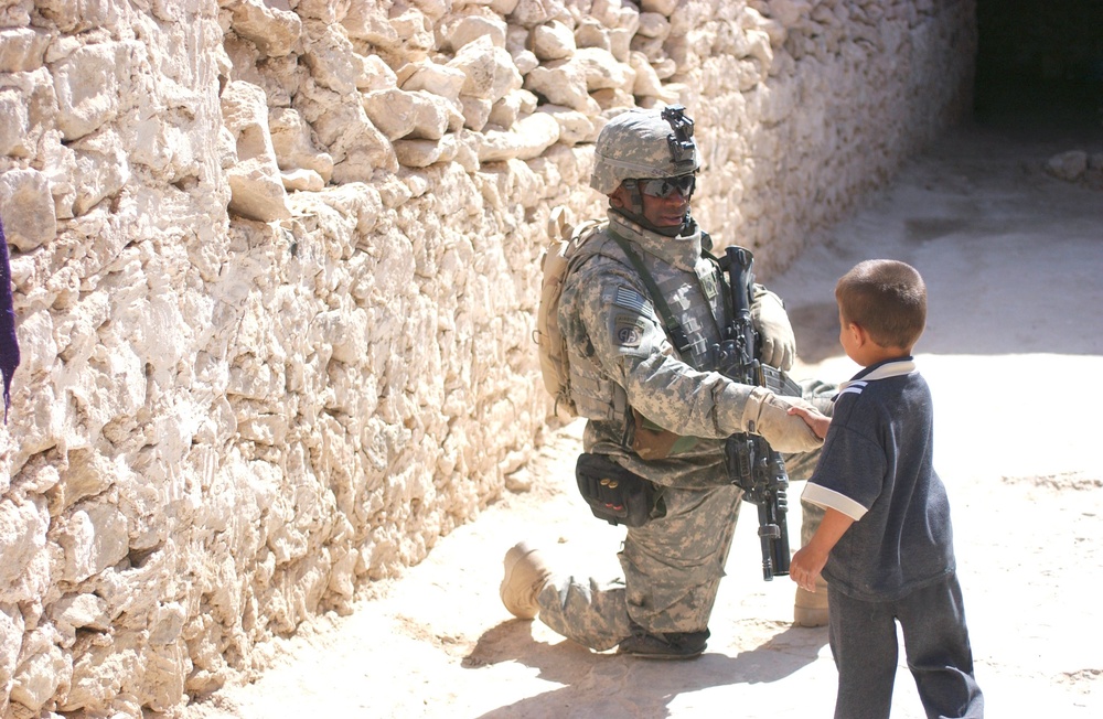 Spc. Nathan K. Edwards shakes the hand of a small boy