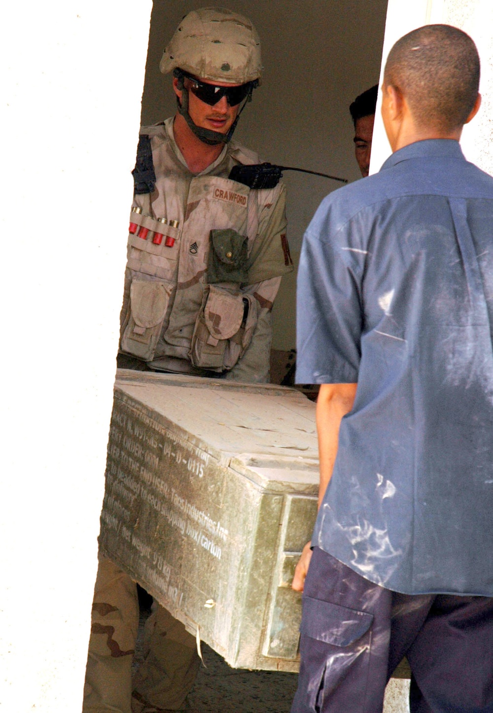 SSG Crawford and an Iraqi patrolman move a crate of ammunition c
