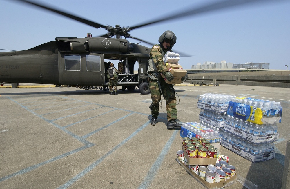 A U.S. Army UH-60 Black Hawk helicopter flight engineer unloads food and wa