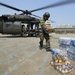 A U.S. Army UH-60 Black Hawk helicopter flight engineer unloads food and wa