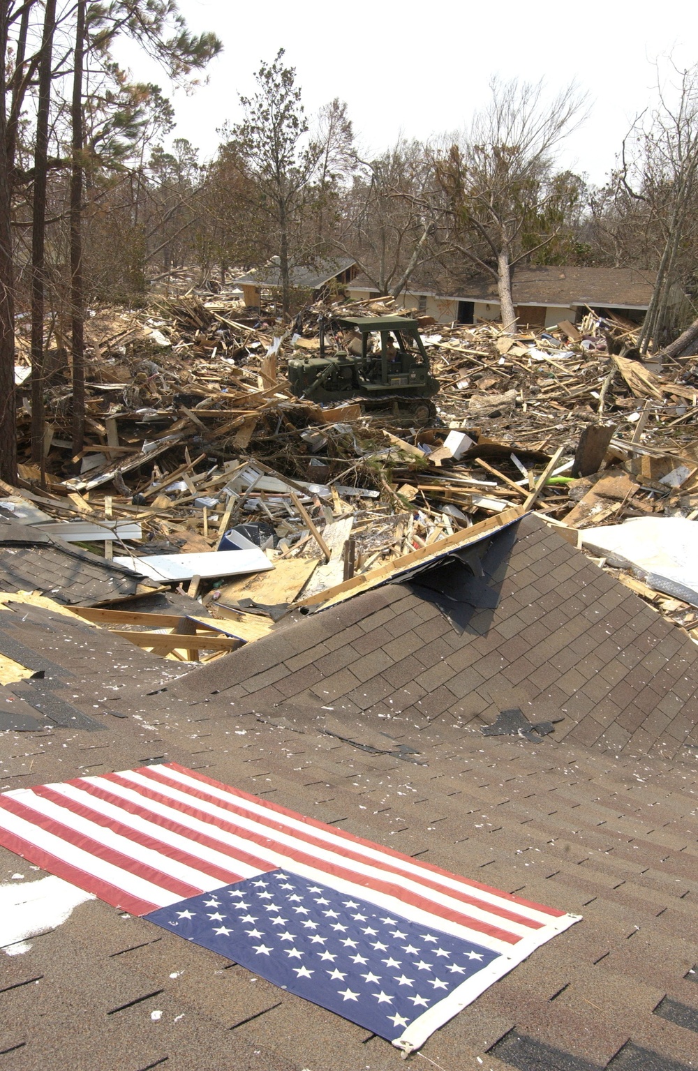 An American Flag sits proudly on the roof of a severely damaged home