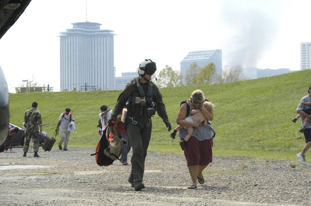 A U.S. Navy air crewman helps a mother and her baby board an MH-53E Sea Dra