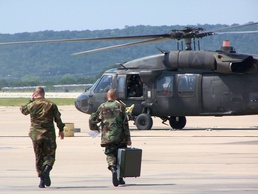 Two Soldiers deliver gear to a waiting UH-60 Blackhawk