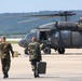Two Soldiers deliver gear to a waiting UH-60 Blackhawk