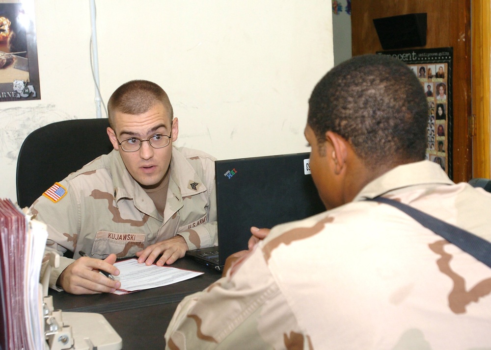Sgt. Andrzej Kujawski helps a Soldier fill out a power of attorney
