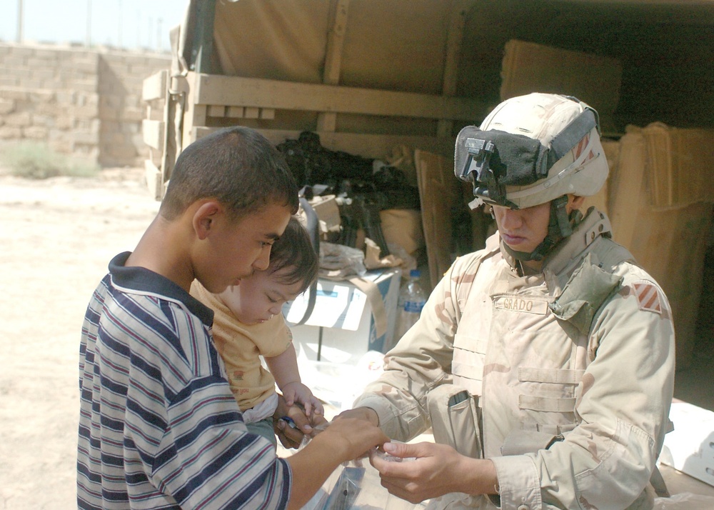 Pfc. Oscar Grado provides a couple of Iraqi kids with medical items