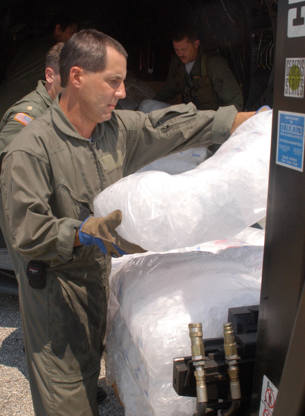 Soldiers and civilians load ice onto a forklift