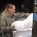 Soldiers and civilians load ice onto a forklift