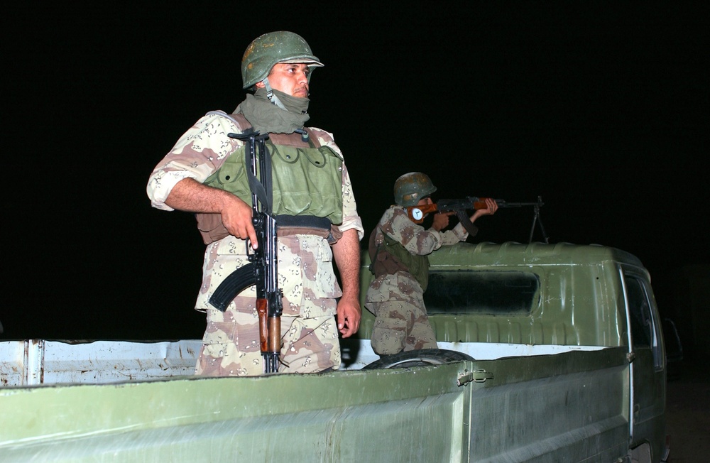 Iraqi army Soldiers pull security while the rest of their team searches sus