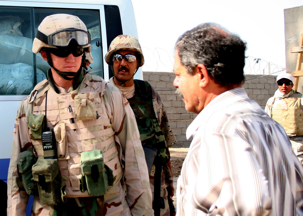 Capt. Jason Belknap greets a Taji area council member after delivering a bu