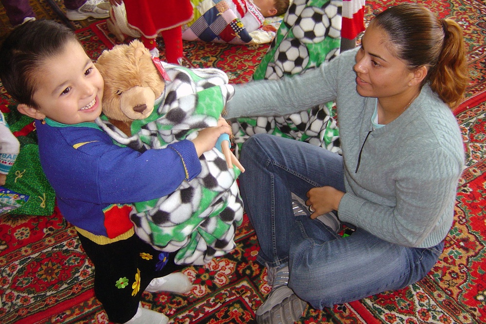 Staff Sgt. Patricia Garcia hands a donated teddy bear wrapped in a donated