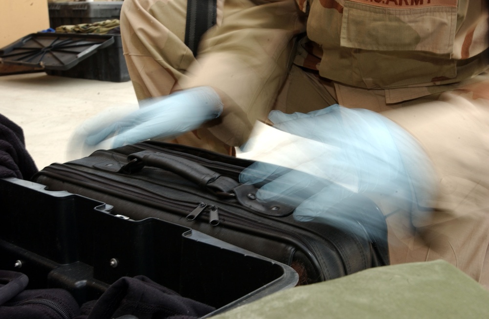 Spc. Patricia Peterson opens a laptop case during her inspection