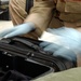 Spc. Patricia Peterson opens a laptop case during her inspection