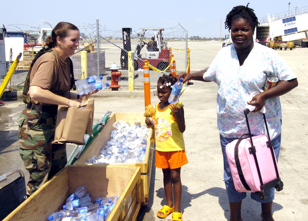 Sgt. Lea Carpenter hands MREs and water to a New Orleans family