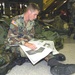 Spc. Nicolas Eigenberger reads the morning paper at his te